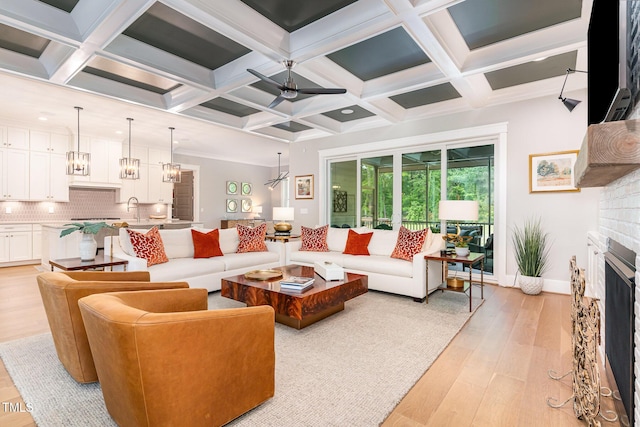 living area featuring baseboards, a fireplace, coffered ceiling, and light wood finished floors