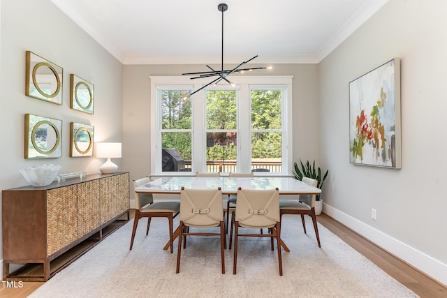 dining room featuring crown molding, baseboards, wood finished floors, and a notable chandelier