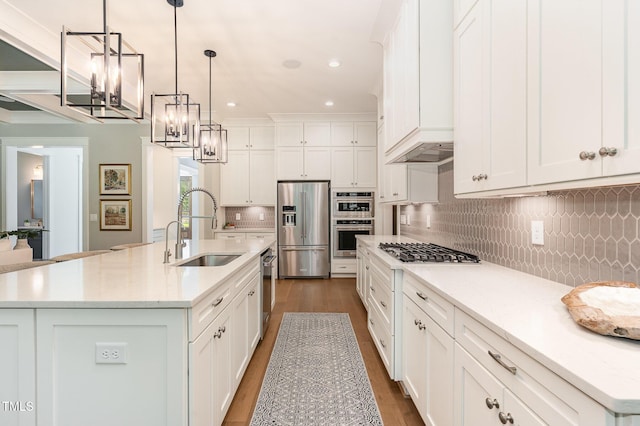 kitchen featuring a sink, stainless steel appliances, wood finished floors, and a chandelier