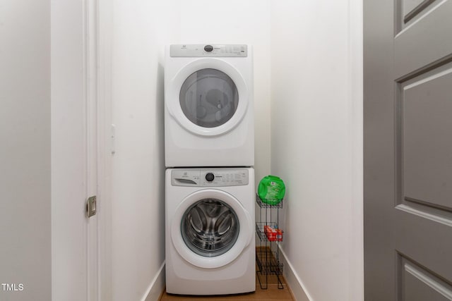 washroom featuring laundry area, stacked washer and clothes dryer, and baseboards