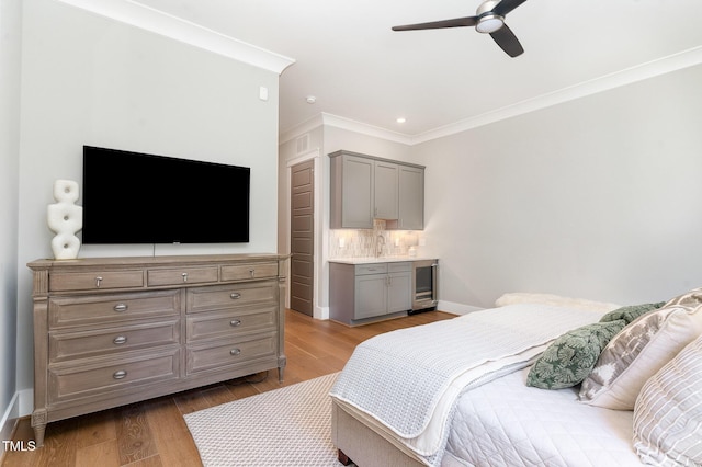 bedroom with crown molding, a ceiling fan, baseboards, and wood finished floors