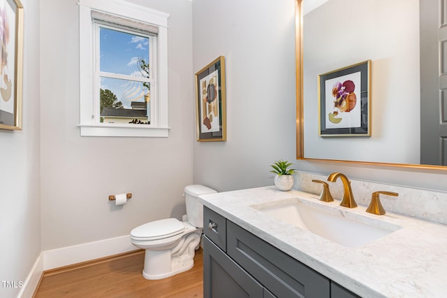 bathroom with vanity, baseboards, wood finished floors, and toilet