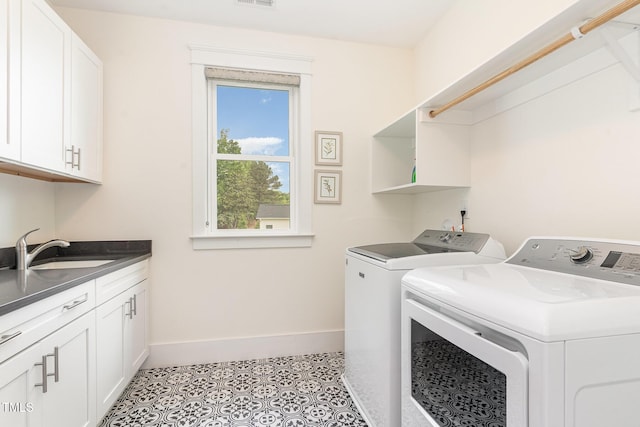 clothes washing area with cabinet space, a sink, baseboards, visible vents, and washing machine and dryer