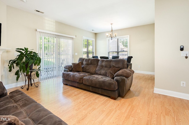 living area featuring an inviting chandelier, baseboards, wood finished floors, and visible vents