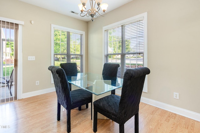 dining area featuring visible vents, light wood-style floors, baseboards, and a chandelier