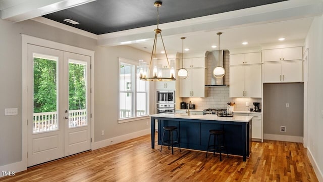 1733 Birdhaven Ln Lot 2217, Wendell, NC 27591 - kitchen with wall chimney range hood, appliances with stainless steel finishes, white cabinetry, light wood-style flooring, and decorative backsplash