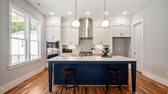1733 Birdhaven Ln Lot 2217, Wendell, NC 27591 - kitchen with wall chimney exhaust hood, tasteful backsplash, white cabinets, light wood-style flooring, and recessed lighting