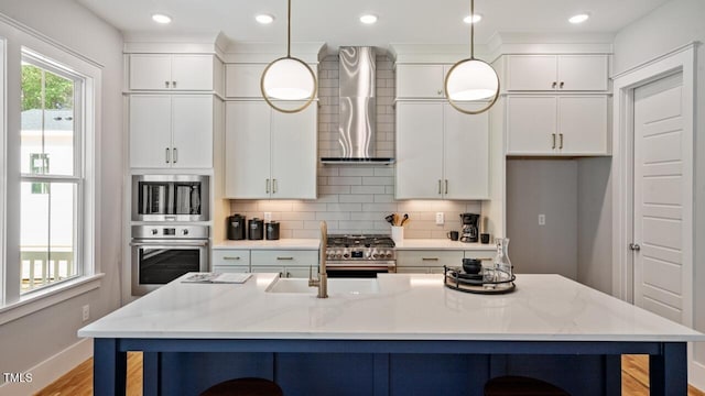 1733 Birdhaven Ln Lot 2217, Wendell, NC 27591 - kitchen with stainless steel appliances, wall chimney range hood, white cabinetry, a breakfast bar area, and recessed lighting