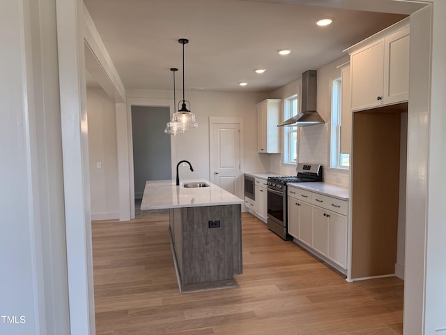 1720 Bright Lantern Way, Wendell, NC 27591 - kitchen with stainless steel appliances, wall chimney range hood, white cabinetry, light wood-style floors, and a kitchen island with sink