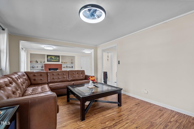 living area featuring light wood finished floors, crown molding, baseboards, and a fireplace
