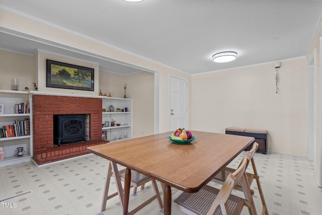 dining area with ornamental molding, light floors, and a wood stove