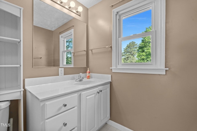 bathroom featuring a textured ceiling, baseboards, vanity, and tile patterned flooring