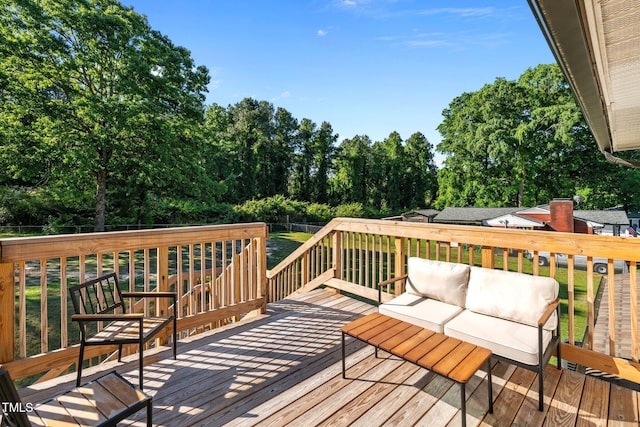 wooden deck featuring an outdoor living space, a fenced backyard, and a lawn