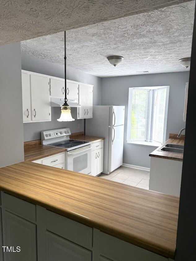 kitchen featuring a sink, white appliances, under cabinet range hood, white cabinetry, and light tile patterned floors