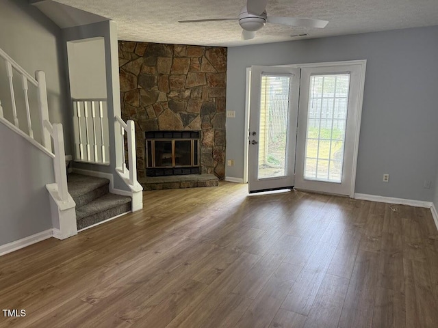 unfurnished living room featuring stairs, a textured ceiling, baseboards, and a ceiling fan