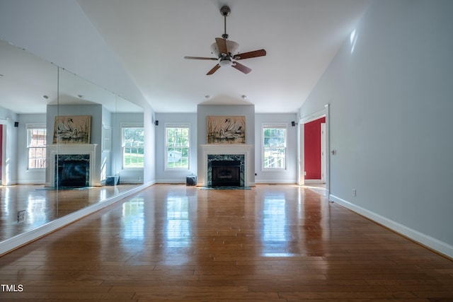 unfurnished living room with a ceiling fan, vaulted ceiling, a premium fireplace, and hardwood / wood-style floors