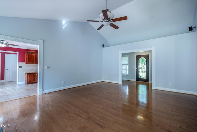 unfurnished living room featuring baseboards, ceiling fan, wood finished floors, and high vaulted ceiling