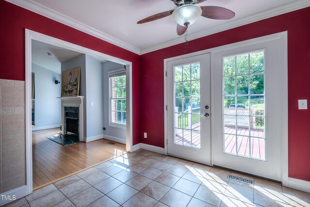 doorway to outside with ceiling fan, baseboards, a high end fireplace, visible vents, and ornamental molding