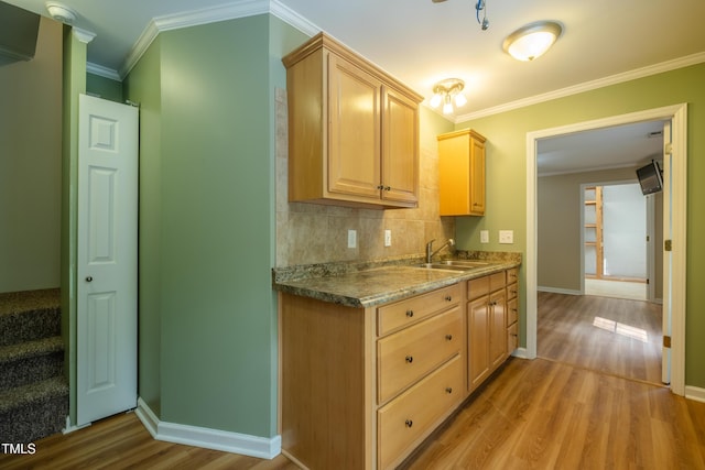 kitchen with baseboards, a sink, light wood finished floors, and light brown cabinets