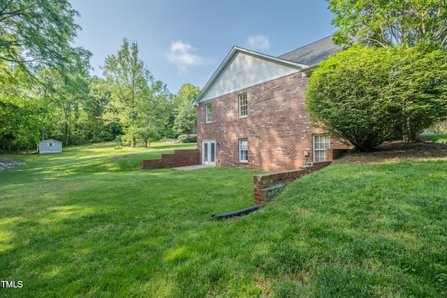 view of property exterior featuring brick siding, a lawn, a shed, and an outbuilding