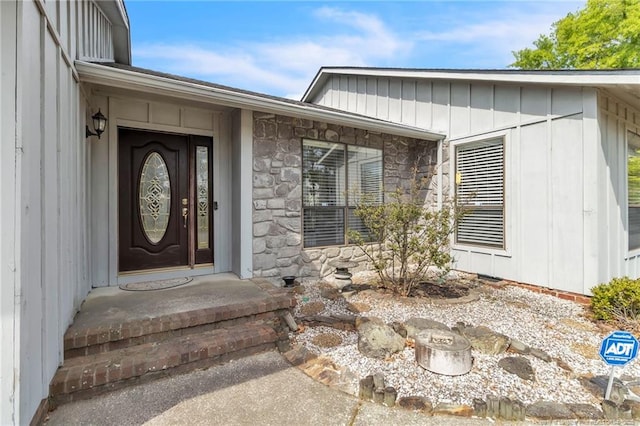 property entrance with board and batten siding and stone siding