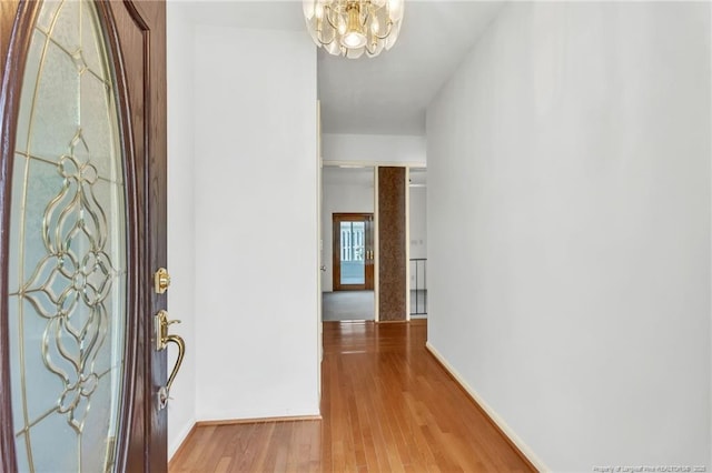 foyer entrance with wood finished floors, a chandelier, and baseboards