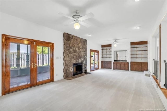 unfurnished living room featuring carpet flooring, a ceiling fan, french doors, and a fireplace