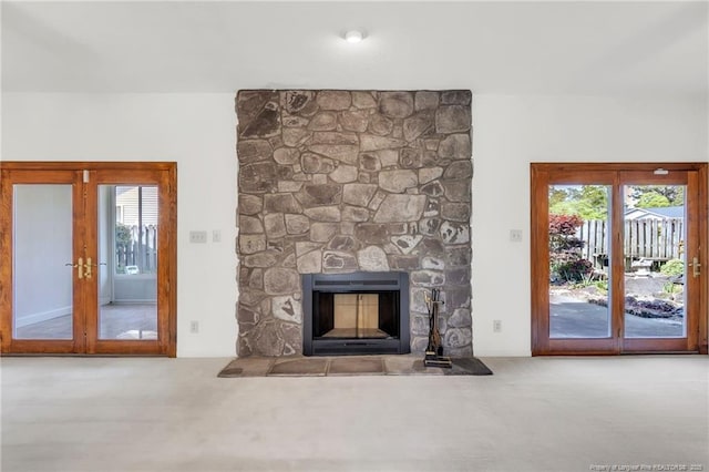 unfurnished living room with carpet flooring, a stone fireplace, and french doors