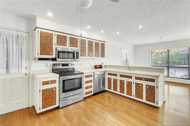 kitchen featuring recessed lighting, stainless steel appliances, light countertops, ceiling fan with notable chandelier, and a peninsula