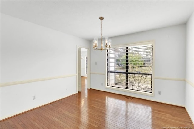 unfurnished dining area with wood-type flooring, a notable chandelier, and visible vents
