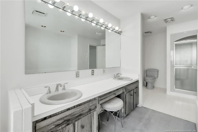 bathroom with toilet, double vanity, a sink, and visible vents