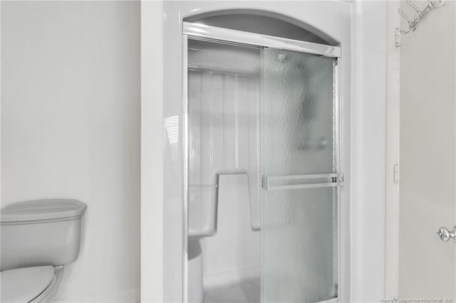 bathroom featuring toilet and a stall shower