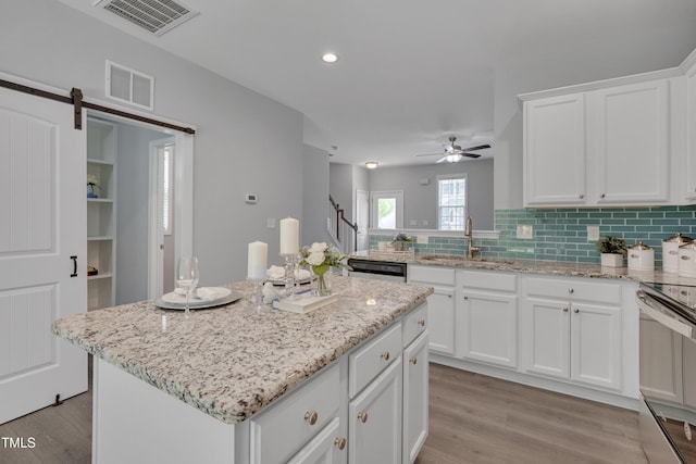 kitchen with a sink, electric range oven, light wood-type flooring, and visible vents