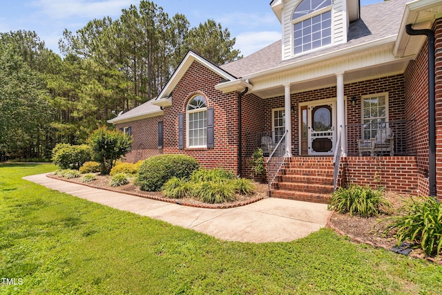 108 Cedarwood Dr, Louisburg, NC 27549 - doorway to property with brick siding, a lawn, covered porch, and a shingled roof