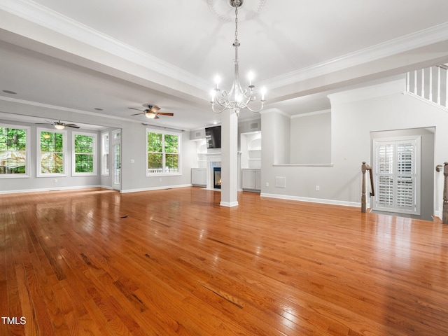 unfurnished living room with light wood-style flooring, baseboards, ornamental molding, a glass covered fireplace, and ceiling fan with notable chandelier