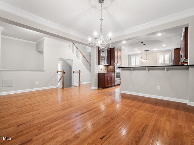 unfurnished living room featuring light wood finished floors, an inviting chandelier, baseboards, and recessed lighting