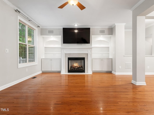 unfurnished living room with a ceiling fan, crown molding, visible vents, and built in shelves