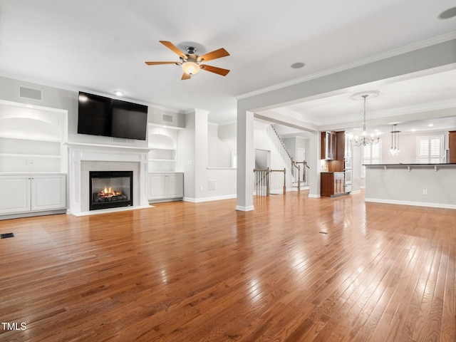 unfurnished living room featuring crown molding, light wood-style floors, visible vents, and ceiling fan with notable chandelier