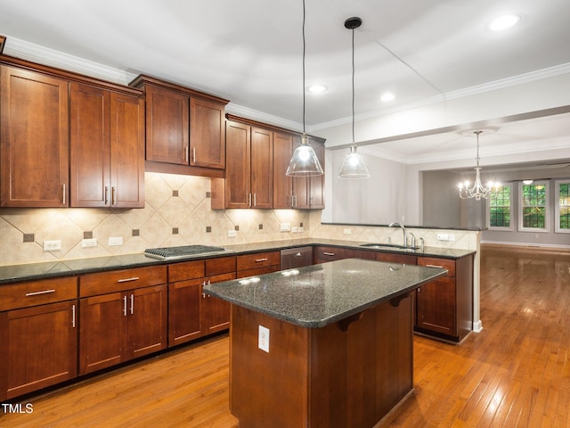 kitchen with light wood-style floors, a peninsula, a sink, and a kitchen island