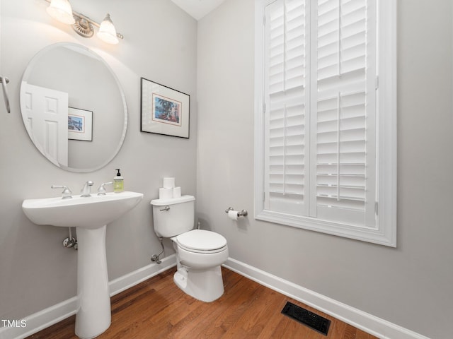 bathroom with wood finished floors, visible vents, baseboards, and toilet