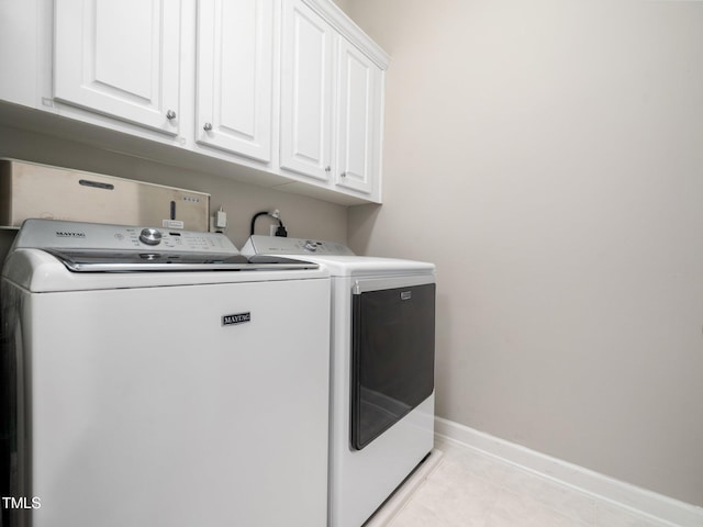 laundry room featuring baseboards, separate washer and dryer, light tile patterned flooring, and cabinet space