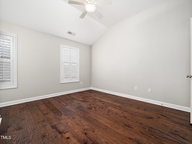spare room with a ceiling fan, lofted ceiling, baseboards, visible vents, and dark wood-style floors