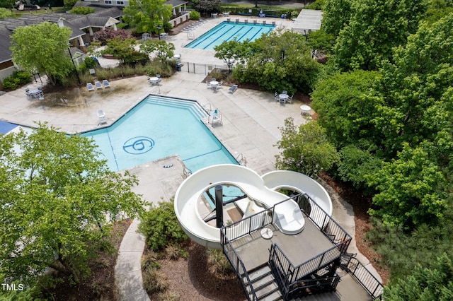 pool with stairs, a patio, a water slide, and fence