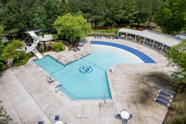 view of pool with a patio area, a forest view, and a water slide