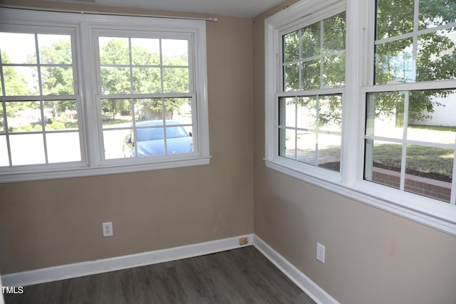 unfurnished room with baseboards, healthy amount of natural light, and dark wood-type flooring