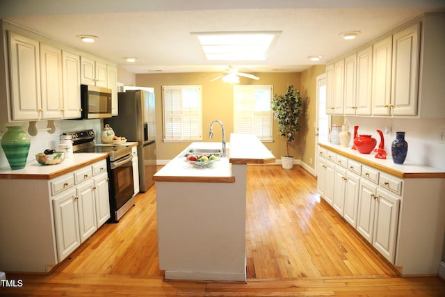 1927 Simpkins Rd, Raleigh, NC 27603 - kitchen featuring stainless steel appliances, light wood-type flooring, an island with sink, light countertops, and white cabinets