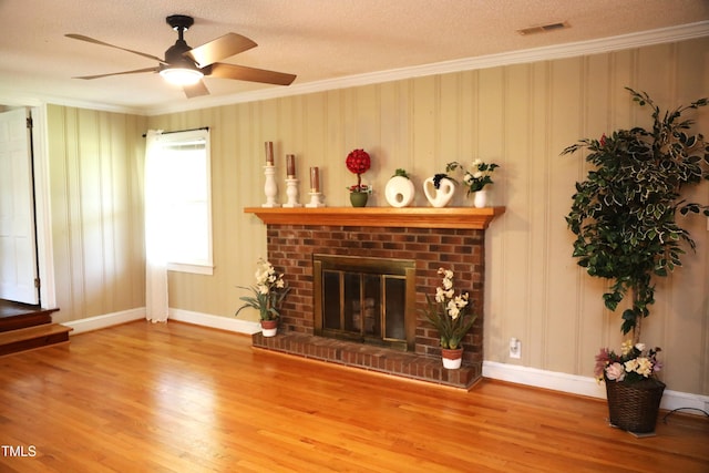 1927 Simpkins Rd, Raleigh, NC 27603 - living room featuring wood finished floors, a textured ceiling, crown molding, a ceiling fan, and a brick fireplace