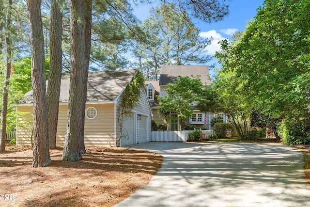 view of front of house featuring fence, a shingled roof, and concrete driveway