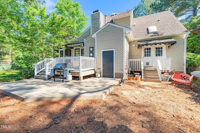 rear view of property with a chimney, roof with shingles, and a deck