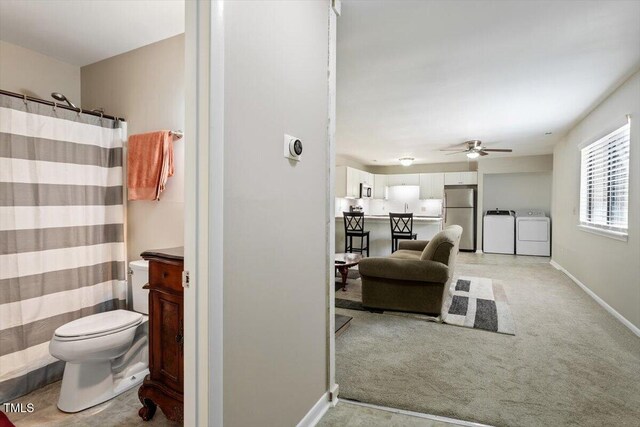 full bathroom with ceiling fan, baseboards, vanity, toilet, and washer and clothes dryer